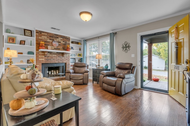 living room with built in features, a brick fireplace, wood-type flooring, and a healthy amount of sunlight