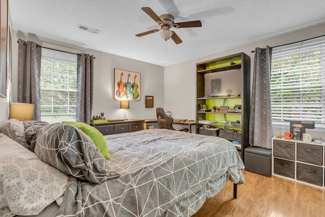 bedroom with ceiling fan, a textured ceiling, and light hardwood / wood-style flooring