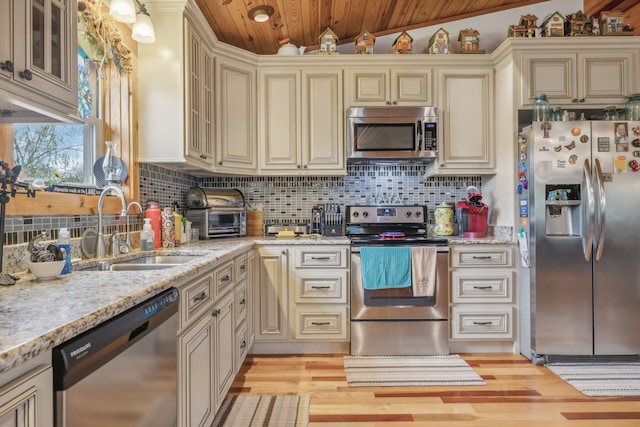 kitchen featuring sink, stainless steel appliances, vaulted ceiling, and cream cabinetry