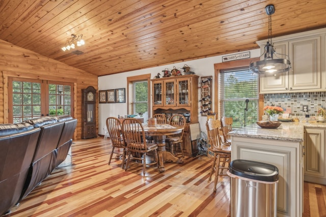 dining space featuring light wood-type flooring, a healthy amount of sunlight, and wooden walls