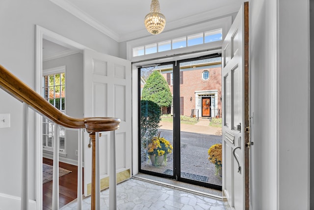 foyer entrance with crown molding and a chandelier