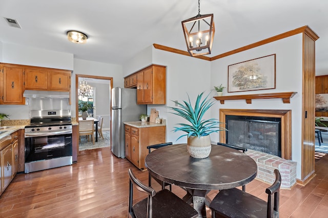 dining area with hardwood / wood-style floors, a chandelier, and a brick fireplace