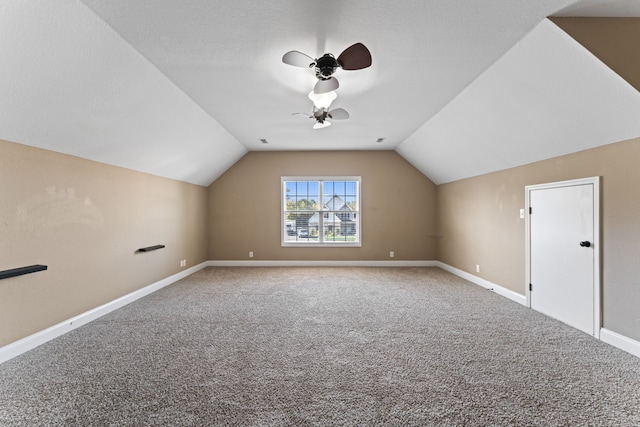 additional living space with carpet, vaulted ceiling, a textured ceiling, and ceiling fan