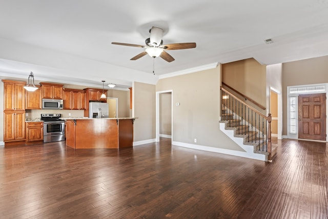 kitchen with appliances with stainless steel finishes, hanging light fixtures, ceiling fan, ornamental molding, and dark hardwood / wood-style floors