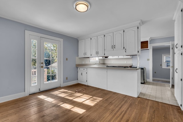 kitchen with ornamental molding, white cabinetry, kitchen peninsula, and light hardwood / wood-style floors