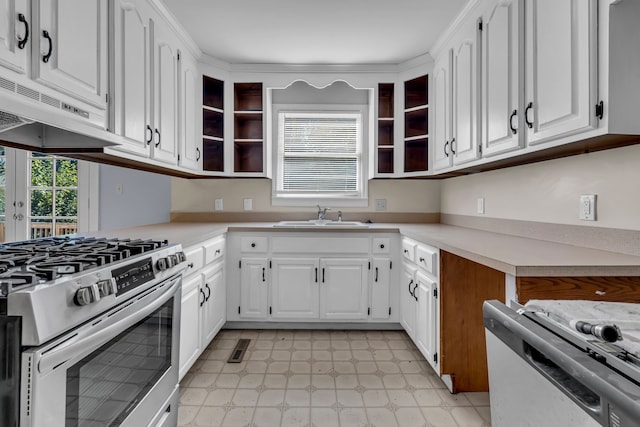 kitchen with stainless steel gas range oven, extractor fan, white cabinetry, white stove, and sink