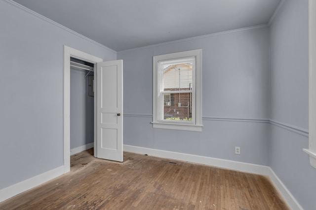 unfurnished bedroom featuring ornamental molding, a closet, and hardwood / wood-style floors