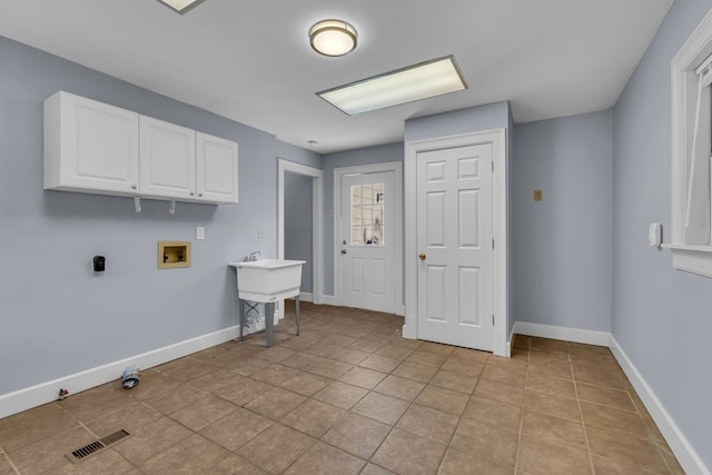 clothes washing area featuring cabinets, washer hookup, and light tile patterned floors