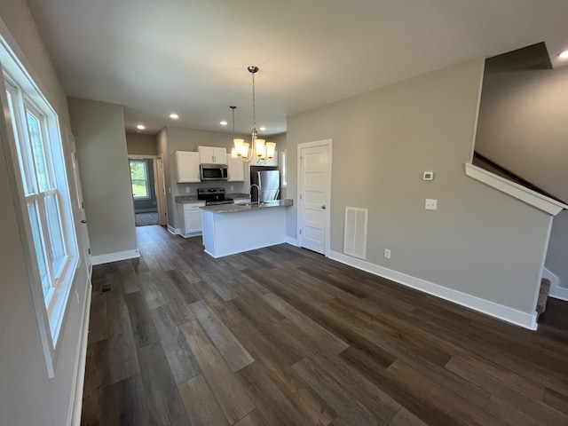 kitchen featuring appliances with stainless steel finishes, white cabinetry, decorative light fixtures, dark wood-type flooring, and a chandelier