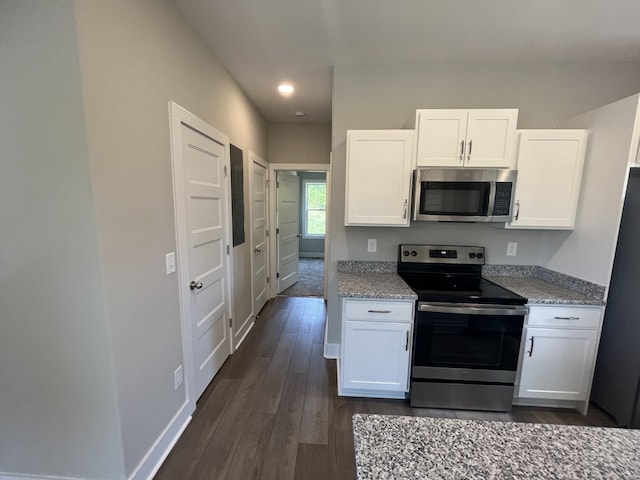 kitchen featuring appliances with stainless steel finishes, white cabinetry, light stone countertops, and dark wood-type flooring