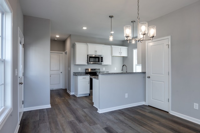 kitchen featuring dark wood-type flooring, a chandelier, decorative light fixtures, white cabinets, and appliances with stainless steel finishes