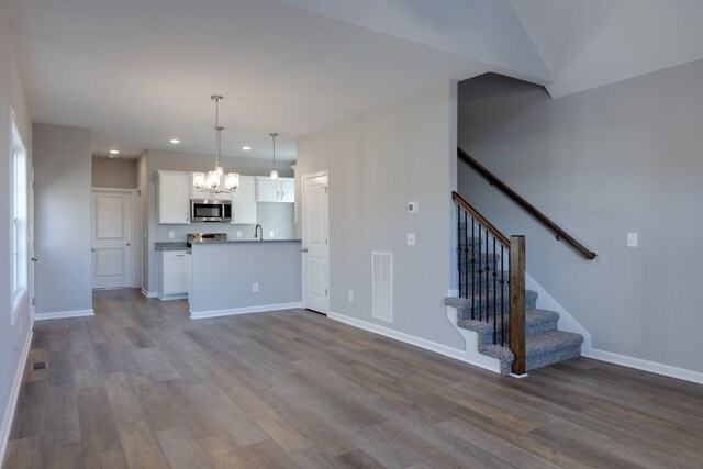 kitchen featuring white cabinetry, pendant lighting, wood-type flooring, and appliances with stainless steel finishes