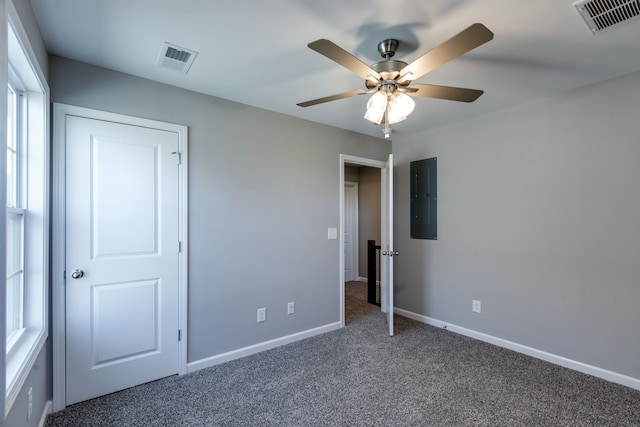 unfurnished bedroom with electric panel, ceiling fan, and dark colored carpet