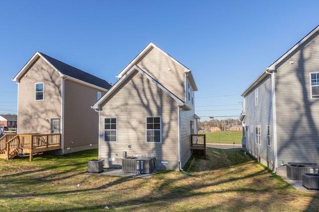 back of property featuring central AC unit, a wooden deck, and a lawn