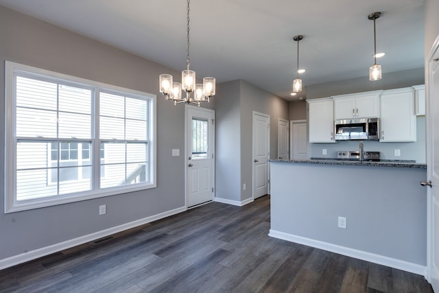 kitchen featuring dark stone counters, white cabinets, dark hardwood / wood-style floors, decorative light fixtures, and a chandelier