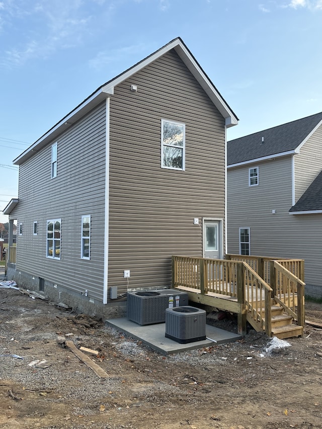 rear view of property featuring a wooden deck, central air condition unit, and a patio area