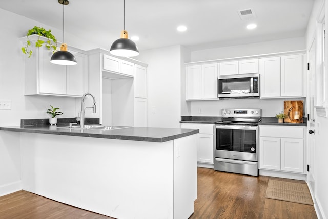 kitchen with appliances with stainless steel finishes, sink, kitchen peninsula, hanging light fixtures, and white cabinets