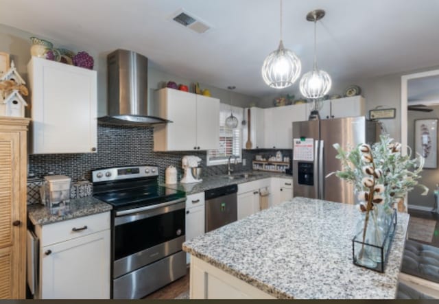 kitchen with wall chimney exhaust hood, white cabinetry, and appliances with stainless steel finishes