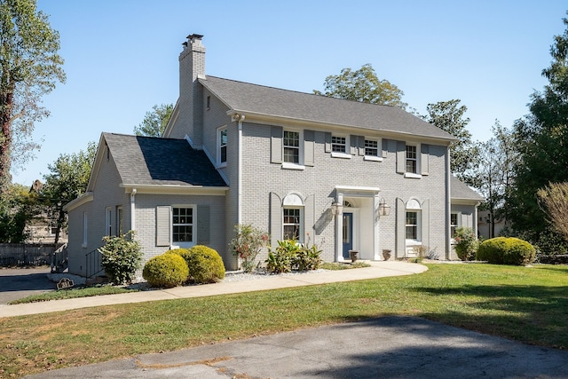 colonial-style house featuring a front lawn