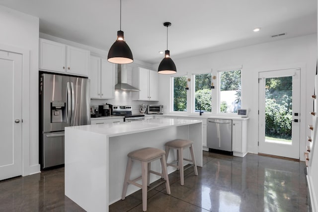 kitchen featuring appliances with stainless steel finishes, wall chimney range hood, white cabinetry, and a healthy amount of sunlight