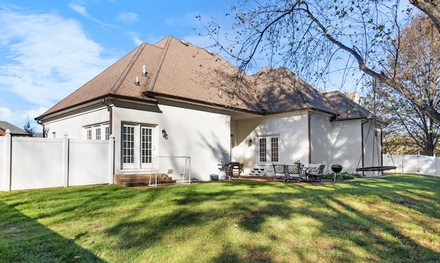 back of property with a trampoline, a patio, and a yard