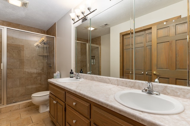 bathroom with toilet, a textured ceiling, vanity, and a shower with door