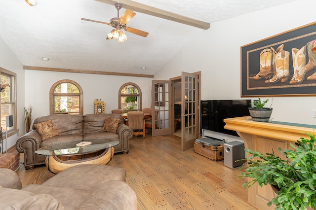 living room featuring french doors, vaulted ceiling with beams, a textured ceiling, light hardwood / wood-style floors, and ceiling fan