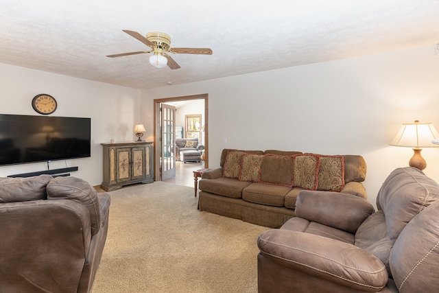 living room featuring a textured ceiling, carpet flooring, and ceiling fan