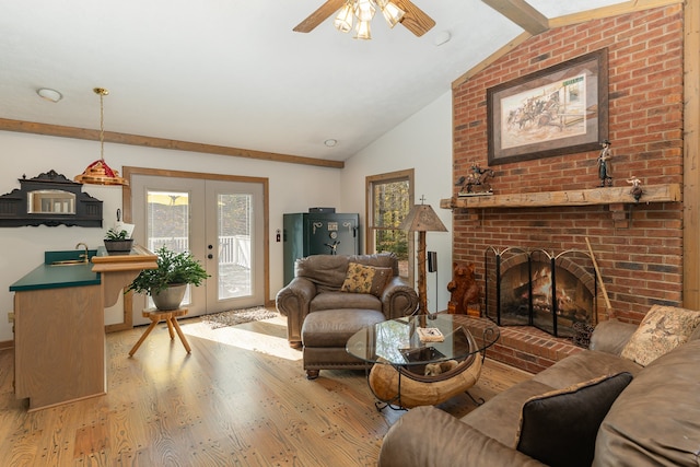 living room featuring a fireplace, french doors, lofted ceiling with beams, ceiling fan, and light hardwood / wood-style flooring