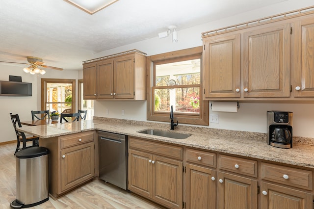 kitchen with stainless steel dishwasher, light hardwood / wood-style floors, kitchen peninsula, and a healthy amount of sunlight