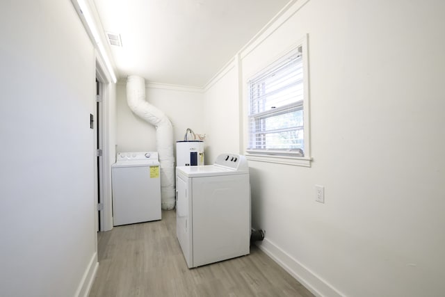 laundry area featuring water heater, ornamental molding, separate washer and dryer, and light wood-type flooring