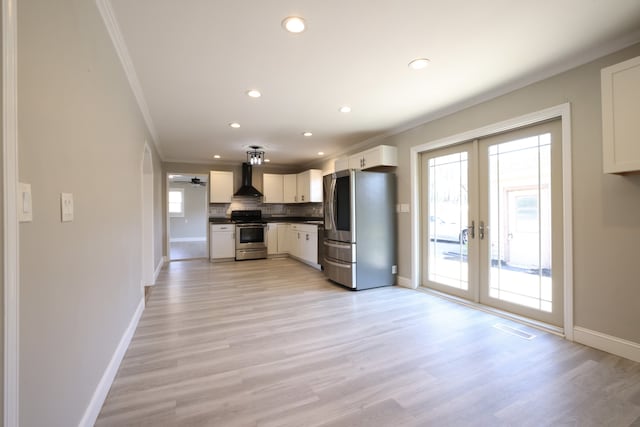 kitchen featuring white cabinets, light hardwood / wood-style floors, wall chimney exhaust hood, french doors, and stainless steel appliances