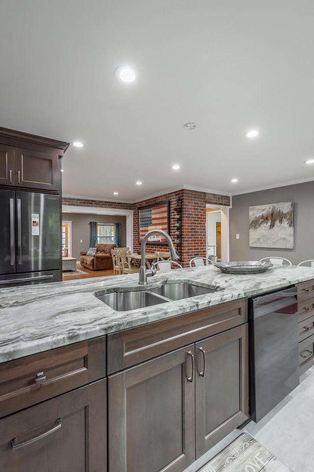 kitchen with light stone countertops, sink, appliances with stainless steel finishes, and dark brown cabinets