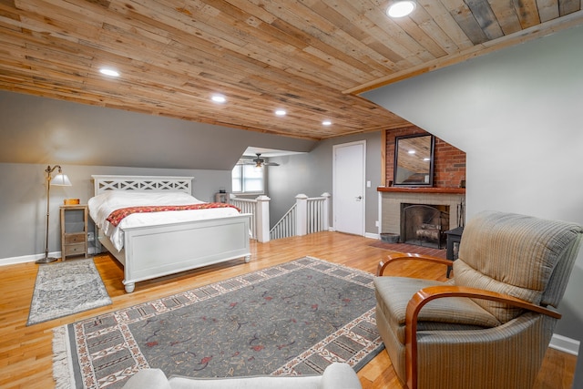 bedroom with vaulted ceiling, wood ceiling, a fireplace, and light hardwood / wood-style floors