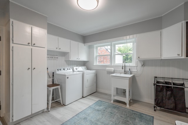 laundry area with washing machine and clothes dryer, light wood-type flooring, and cabinets