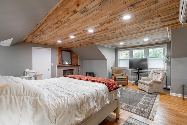 bedroom with wood ceiling, a brick fireplace, light wood-type flooring, and vaulted ceiling