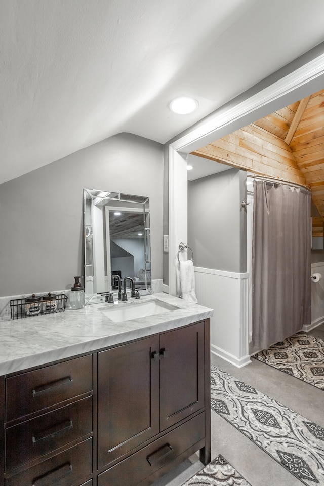 bathroom featuring vanity, wooden walls, vaulted ceiling, and concrete flooring