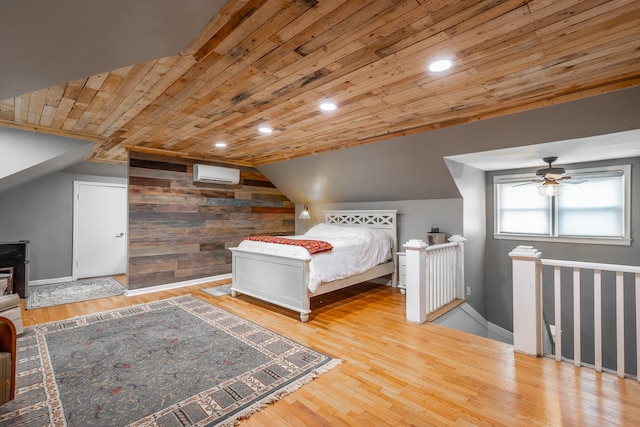 bedroom with wood ceiling, vaulted ceiling, wood walls, an AC wall unit, and light hardwood / wood-style floors