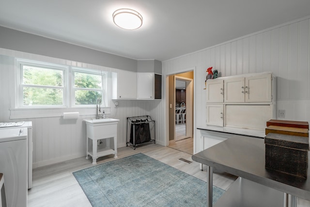 kitchen with light hardwood / wood-style floors, white cabinets, and washing machine and dryer