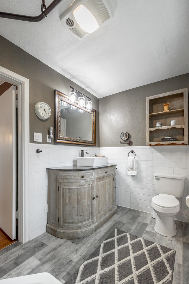 bathroom featuring vanity, hardwood / wood-style floors, toilet, and tile walls