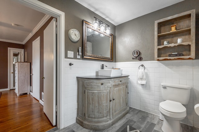 bathroom with hardwood / wood-style floors, toilet, tile walls, vanity, and crown molding