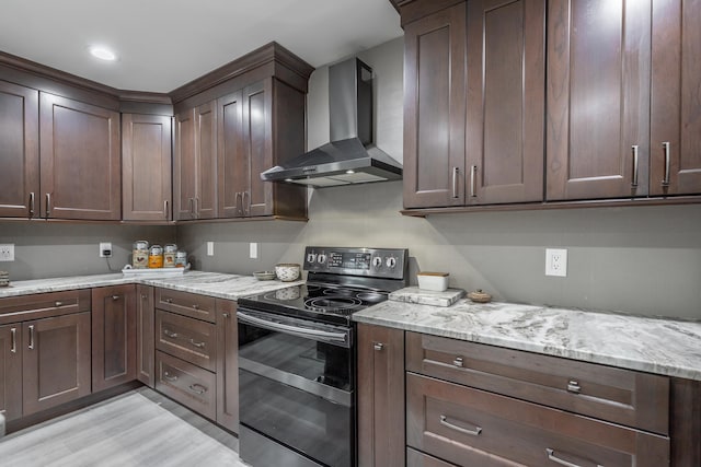 kitchen featuring light hardwood / wood-style flooring, wall chimney exhaust hood, electric range, and light stone counters