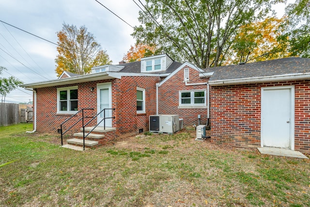 rear view of property featuring a yard and central AC unit