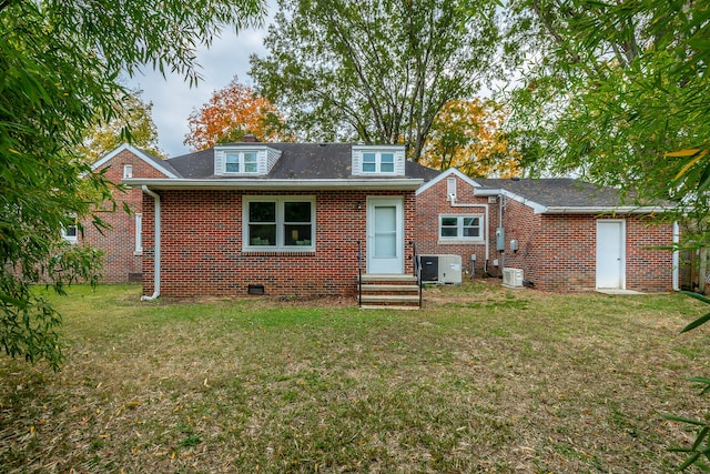 rear view of house with central air condition unit and a yard