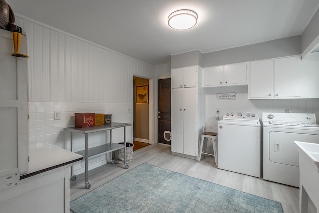 washroom featuring light hardwood / wood-style flooring, cabinets, and washer and clothes dryer