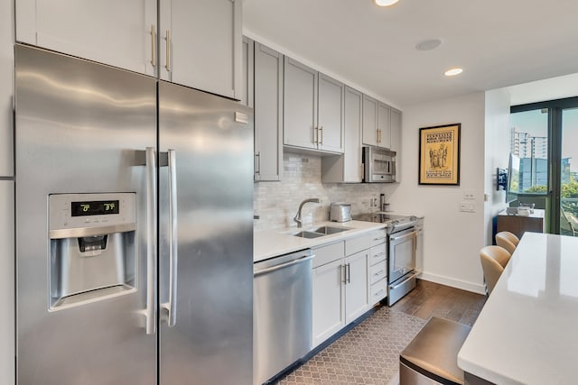 kitchen with gray cabinetry, stainless steel appliances, sink, dark hardwood / wood-style flooring, and tasteful backsplash