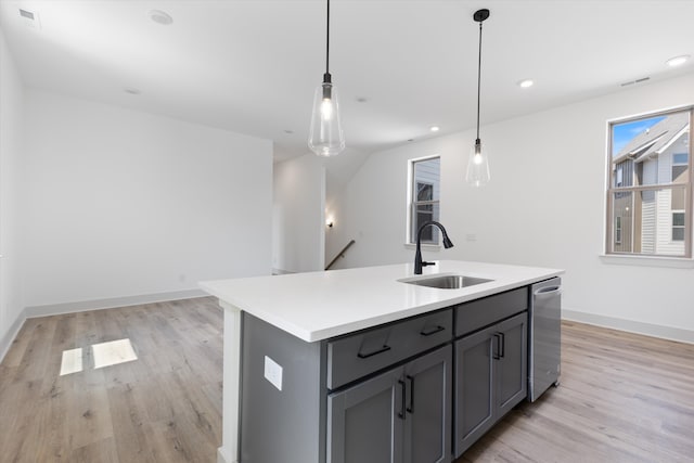 kitchen with hanging light fixtures, an island with sink, stainless steel dishwasher, light hardwood / wood-style flooring, and sink