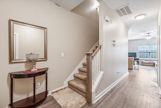 stairway with wood-type flooring and ceiling fan