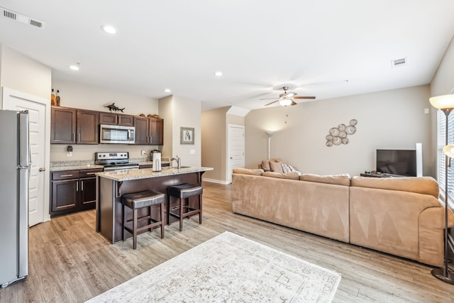 living room with light hardwood / wood-style floors, ceiling fan, and sink