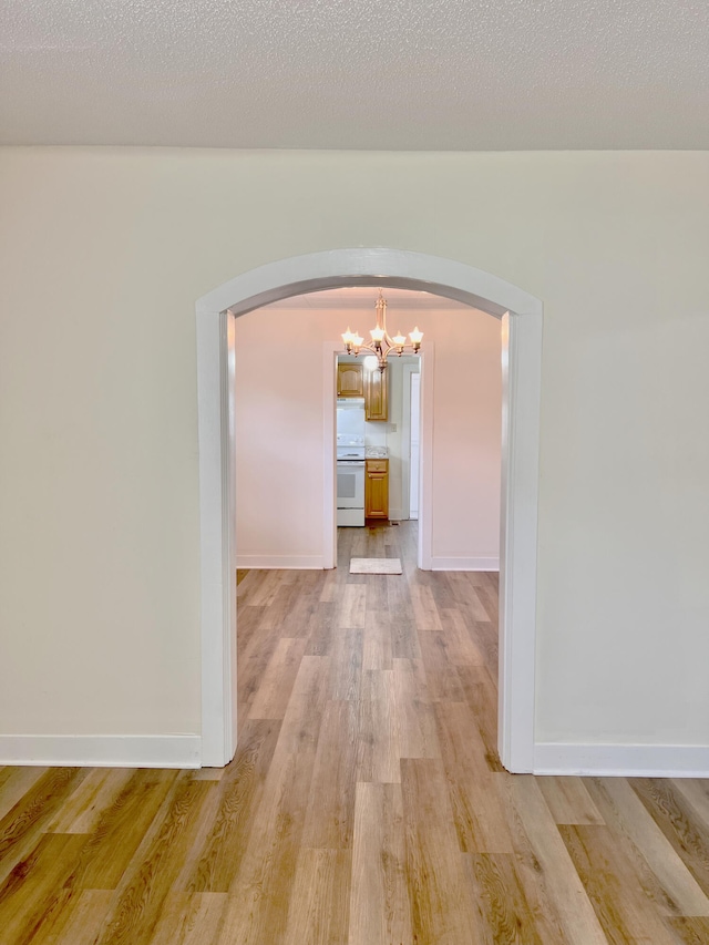 interior space featuring light hardwood / wood-style flooring, a textured ceiling, and a notable chandelier